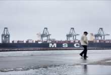 A large container ship arrives at Aarhus Port, loaded with cargo containers.