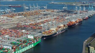 A large container ship is docked at a busy port terminal with multiple cranes.