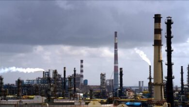 Crude oil barrels are stacked in an industrial storage facility.