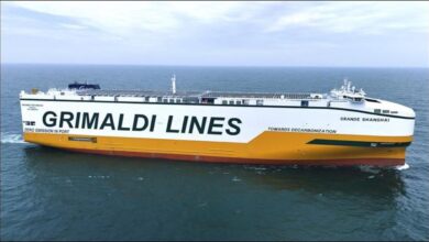 A large Grimaldi Group car carrier ship sails on the open ocean.