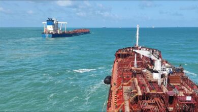 A bunker tanker delivers fuel to a large cargo ship at sea.