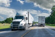 Numerous semi-trucks travel on a highway, illustrating freight market capacity.