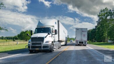 Numerous semi-trucks travel on a highway, illustrating freight market capacity.