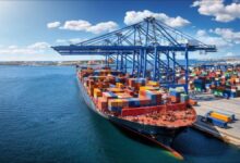 A large container ship loaded with cargo containers sails on the ocean.