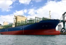A large container ship from HJSC sailing at sea, equipped with scrubber technology.