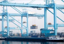 Large container ships docked at a busy port terminal with multiple gantry cranes.