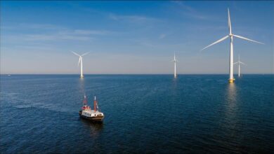 A cargo ship at sea with green energy symbols, representing IMO GreenVoyage2050.