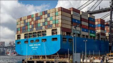 A large container ship packed with colorful containers navigates the ocean.