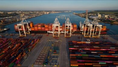 A large Hapag-Lloyd container ship carrying cargo sails across the ocean.