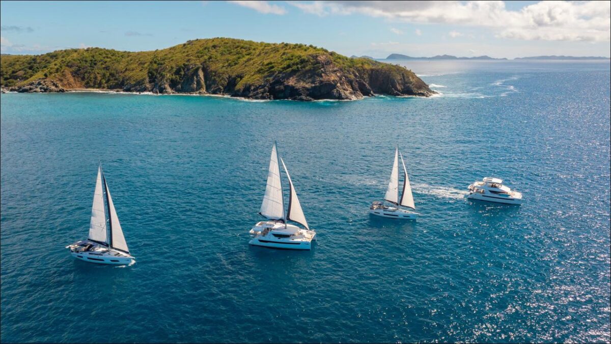 A fleet of The Moorings catamarans docked in a sunny, tropical bay.