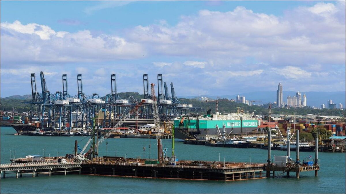 Cargo cranes load containers onto a large ship at a busy Panama port.