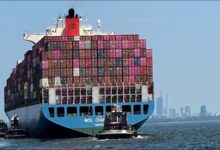 A large container ship transports goods across the ocean, representing global trade.