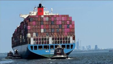 A large container ship transports goods across the ocean, representing global trade.