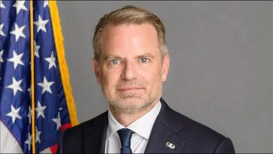 A massive cargo ship, laden with shipping containers, sails on the ocean.