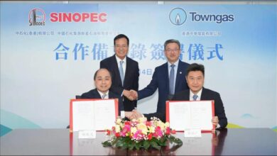 Towngas and Sinopec representatives shake hands, symbolizing their partnership for green fuel initiatives.