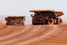 An expansive open-pit mine showing terraced earth and large excavation vehicles.