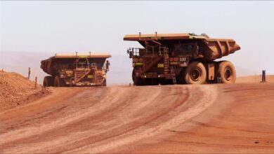 An expansive open-pit mine showing terraced earth and large excavation vehicles.