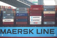 A large Maersk container ship sails on the ocean, loaded with shipping containers.