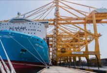 The Maersk Anne container ship sails across the ocean under a blue sky.