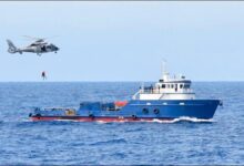 French Navy personnel inspect large drug bales seized on a vessel at sea.