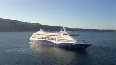 The Celestyal Discovery cruise ship sails on calm blue water.