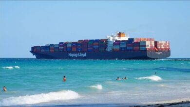 A Hapag-Lloyd container ship full of cargo containers sails on the ocean.