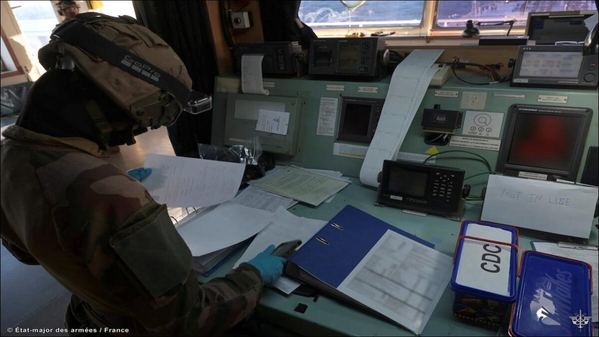 A large oil tanker at sea with a military helicopter overhead during a maritime interception.
