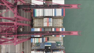A large container ship loaded with colorful containers sails on the ocean.
