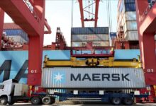 Shipping containers stacked high at a bustling global port terminal.