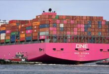 A large magenta ONE container ship loaded with cargo, sailing at sea.
