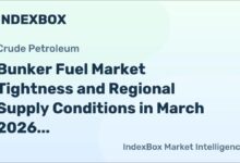 Bunker vessel refueling a large cargo ship in a busy Asian port.