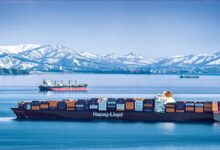 A large Hapag-Lloyd container ship laden with cargo sails through open waters.