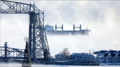 A large freighter pushes through thick ice on Lake Superior, delaying maritime shipping.