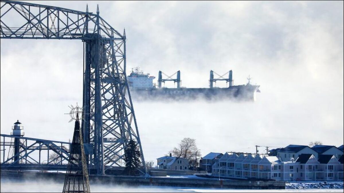 A large freighter pushes through thick ice on Lake Superior, delaying maritime shipping.