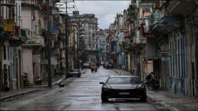 A large oil tanker sails across the sea under a cloudy sky.