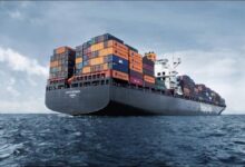 A large Hapag-Lloyd container ship carries cargo through a port.