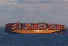 A large Hapag-Lloyd container ship sails on the ocean, representing global shipping.