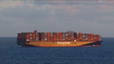 A large Hapag-Lloyd container ship sails on the ocean, representing global shipping.