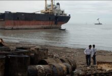 A large cargo ship being dismantled on a sandy beach at a Bangladesh ship recycling yard.