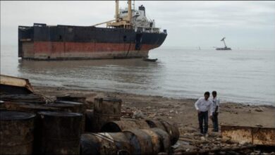 A large cargo ship being dismantled on a sandy beach at a Bangladesh ship recycling yard.