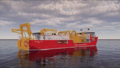 A large, modern Nexans cable-laying vessel on calm blue water.