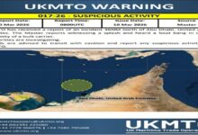 A large bulk carrier ship navigates calm blue waters.