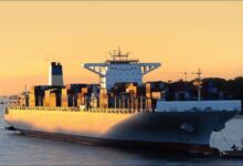 A large Seaspan container ship laden with cargo sails through calm waters.