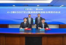 A modern feeder container ship with stacked containers sails on the ocean.