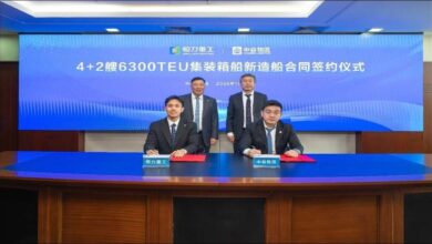 A modern feeder container ship with stacked containers sails on the ocean.