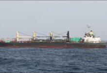 A large bulker engulfed in thick smoke and flames from a fire at sea.