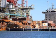 Large cargo ship being dismantled for scrap at an industrial breaking yard.