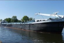 Inland cargo vessel Sola Gratia navigating a waterway near Antwerp.