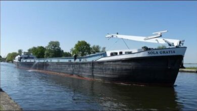 Inland cargo vessel Sola Gratia navigating a waterway near Antwerp.