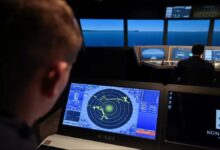 A detailed view of a Kongsberg K-Sim Navigation maritime simulator used for cadet training.